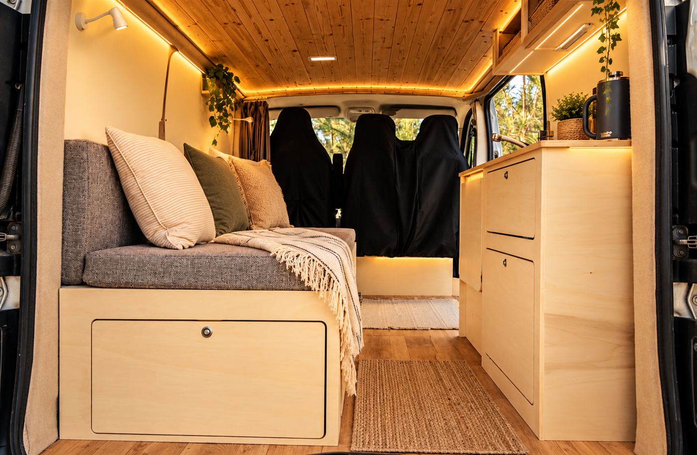 Camper Rústica: techo de madera con iluminación LED cálida, banco con almacenaje, cocina de contrachapado y textiles naturales