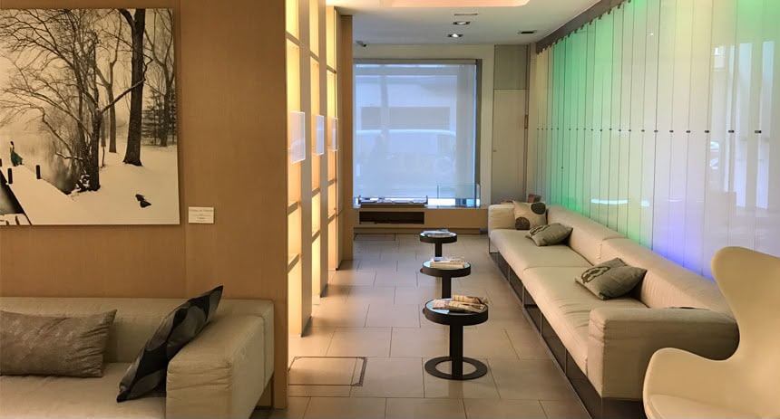Recepción con sofás, mesas auxiliares, paneles de madera clara e iluminación ambiental