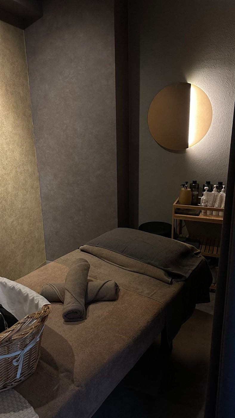 Cabina de masaje con paredes de microcemento y aplique circular de luz cálida